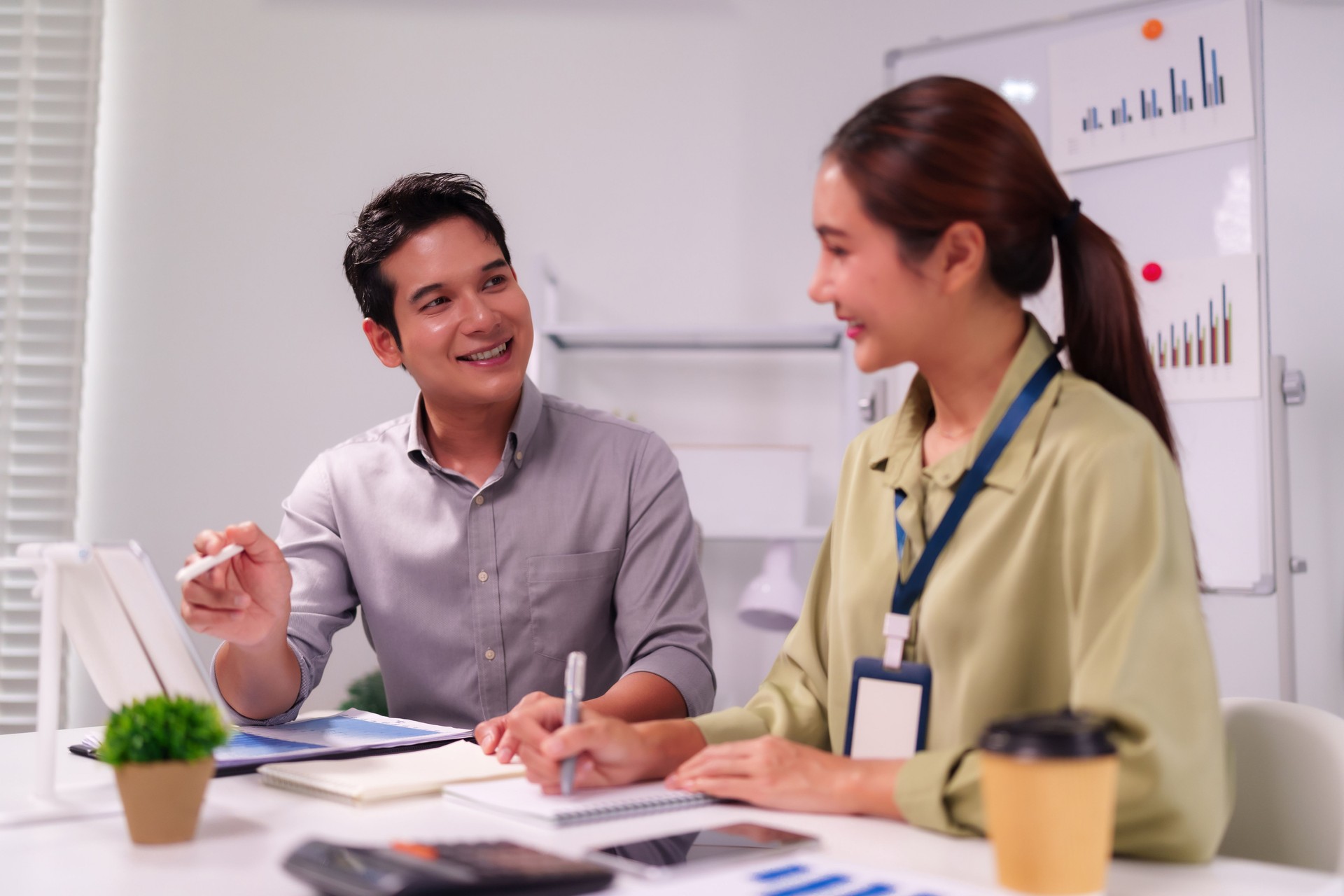 Asian business professionals collaborate on project strategy in modern office discussing ideas for company growth